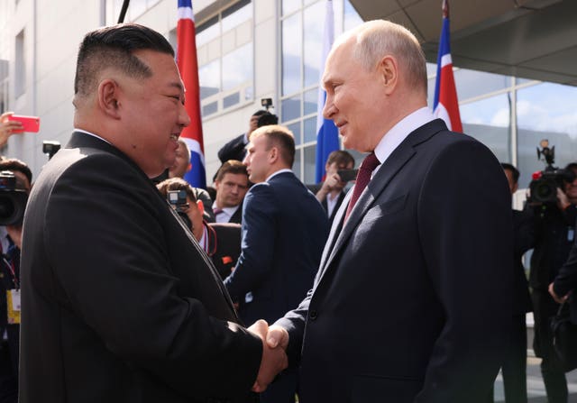 Vladimir Putin and Kim Jong Un shake hands