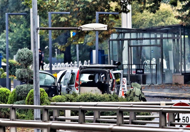 A bomb disposal expert works next to a car after an explosion in Ankara