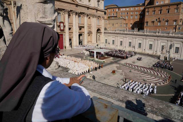 A nun watches for a terrace as Pope Francis presides over mass