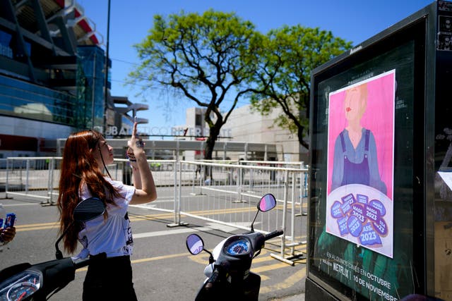 A fan of Taylor Swift takes a picture of a presidential election campaign sign that reads Massa 2023