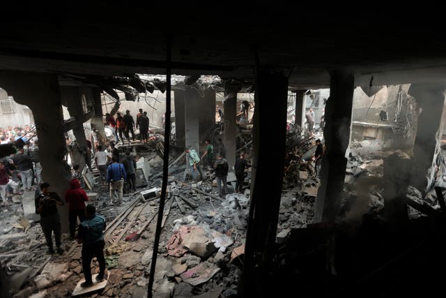 Palestinians look for survivors inside the remains of a destroyed building following an Israeli airstrike in Khan Younis refugee camp, southern Gaza Strip, on Saturday