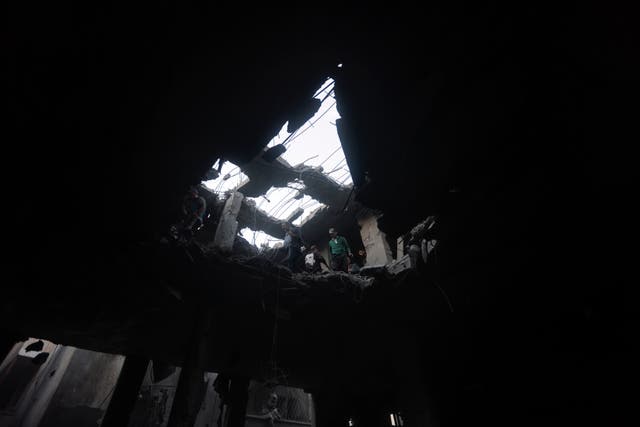 Palestinians look for survivors inside the remains of a destroyed building following an Israeli airstrike in Khan Younis refugee camp, southern Gaza Strip, on Saturday