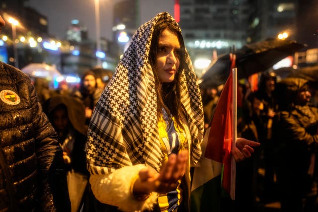 A woman prays during heavy rain during a pro-Palestinian protest outside the Israeli consulate in Istanbul on Saturday