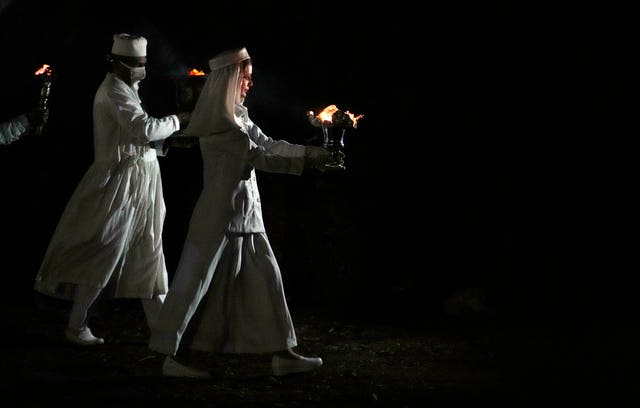 Zoroastrian priests prepare to set fire to a pile of wood