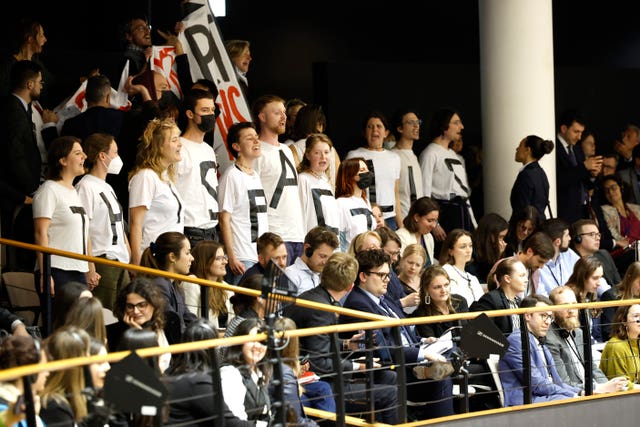 Demonstrators wear a message on their shirts which reads 'his pact kills' while standing in the visitors' gallery, as Members of the European Parliament participate in a series of votes, during a plenary session at the European Parliament in Brussels