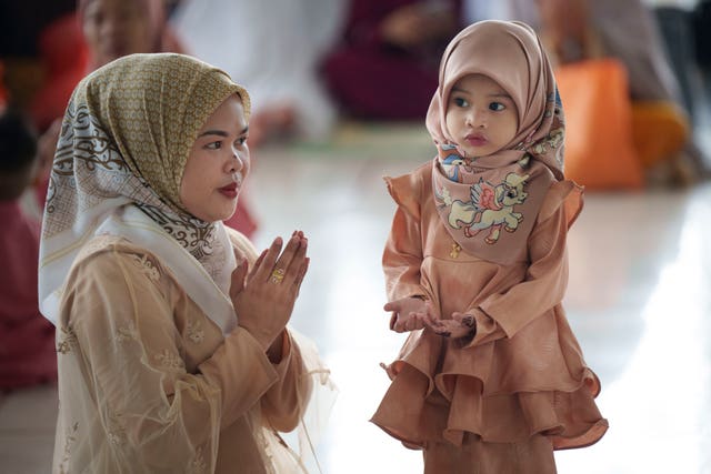 A Muslim woman shows her daughter how to pray 