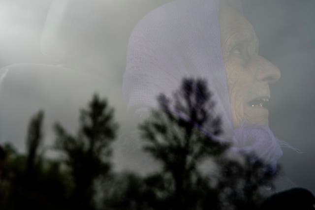 Olga, 79, looks though the window of a car as trees are reflected during her evacuation after her house was heavily damaged by a Russian air strike in Lukiantsi, Kharkiv region, Ukraine