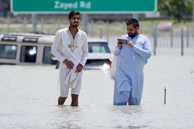 Two men walk through floodwater in Dubai 