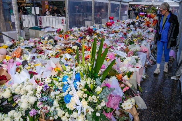 A woman walks past flowers at a tribute for the victims of Saturday’s knife attack at Bondi Junction