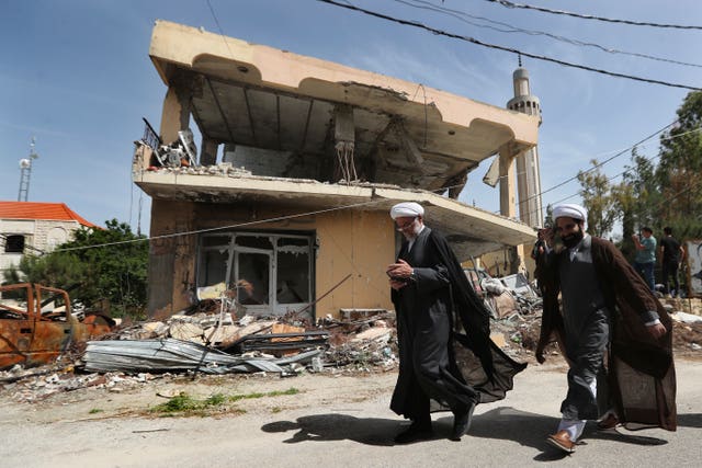 Shiite clerics pass in front of a house that was destroyed by an Israeli airstrike, in Hanine village, south Lebanon 