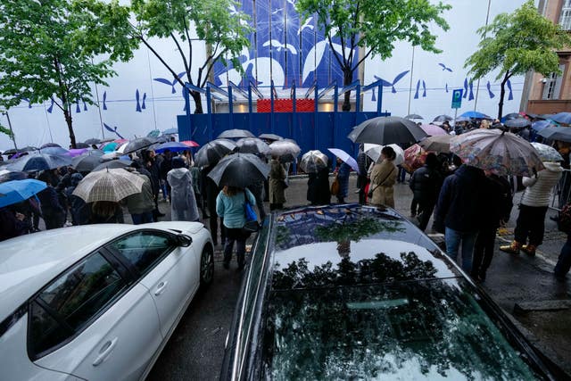 People gather in front of a school during a memorial ceremony