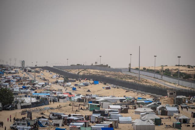 Palestinians displaced by the Israeli air and ground offensive on the Gaza Strip walk through a makeshift tent camp in Rafah, on the border with Egypt