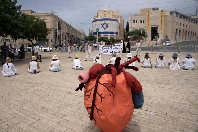 Women activists hold a silent protest with placards in Arabic, Hebrew and English calling for a ceasefire in the Gaza Strip and safety, freedom and equality for Israelis and Palestinians, outside of the walls of the Old City of Jerusalem