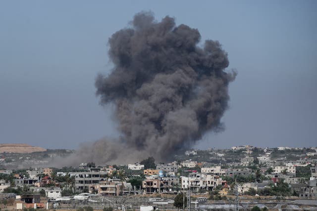 Smoke rises from a cluster of buildings in the distance
