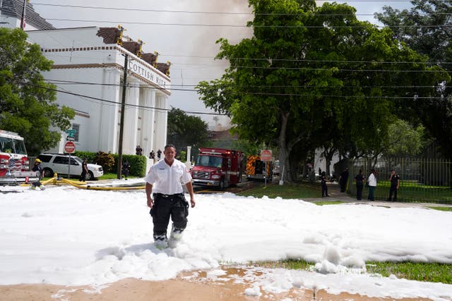 A firefighter walks from the scene of the blaze in Miami with foam across the ground