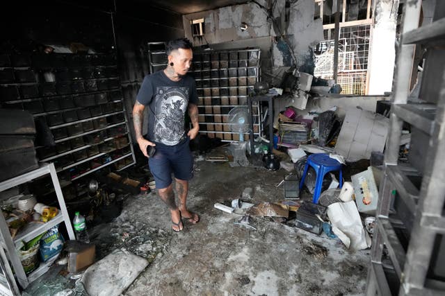 The owner of a pet shop surveys damage after a fire at Chatuchak Weekend Market, one of the most famous markets in Bangkok, Thailand