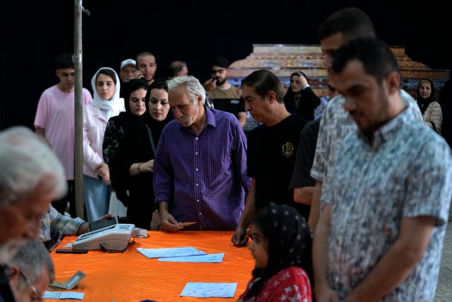 People line up to get their ballots to vote in the presidential election at a polling station in Tehran