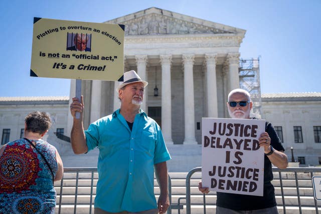 Two protesters outside the US Supreme Court with placards