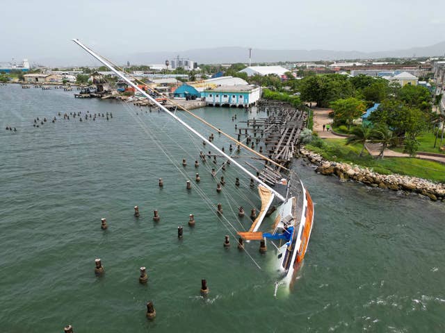 A boat damaged by Hurricane Beryl lays on its side at a dock in Kingston, Jamaica