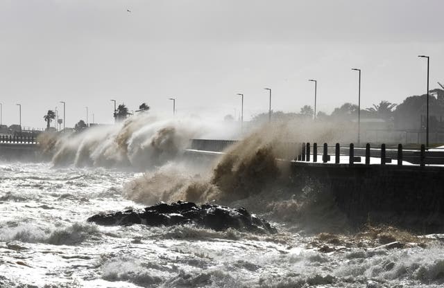 Waves crash over the promenade