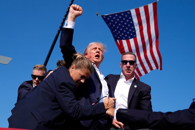 Donald Trump raises his fist, surrounded by secret service agents