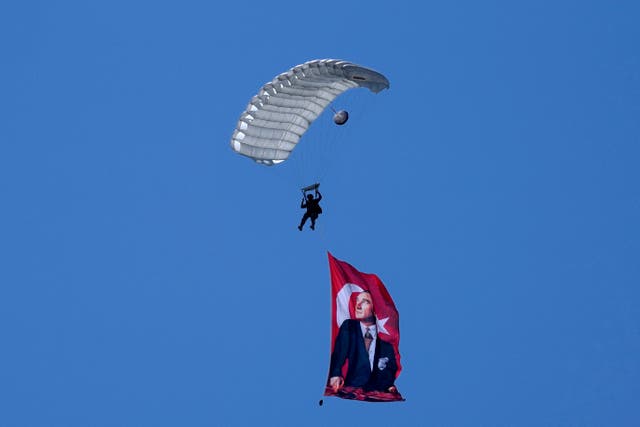 A Turkish parachuter prepares for a landing as fly over the military parade with a Turkish flag