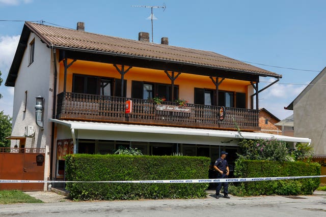 A police officer stands outside a building with a wooden terrace