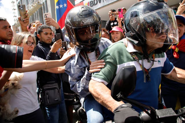 Ms Machado is driven away on a motorbike at the end of the rally