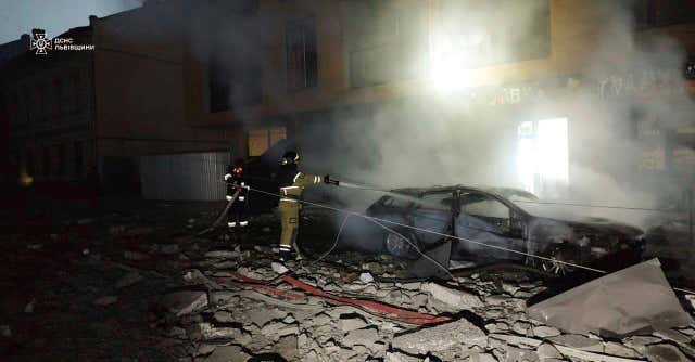 A rescue worker extinguishes a fire in a car destroyed by a Russian strike in Lviv, Ukraine