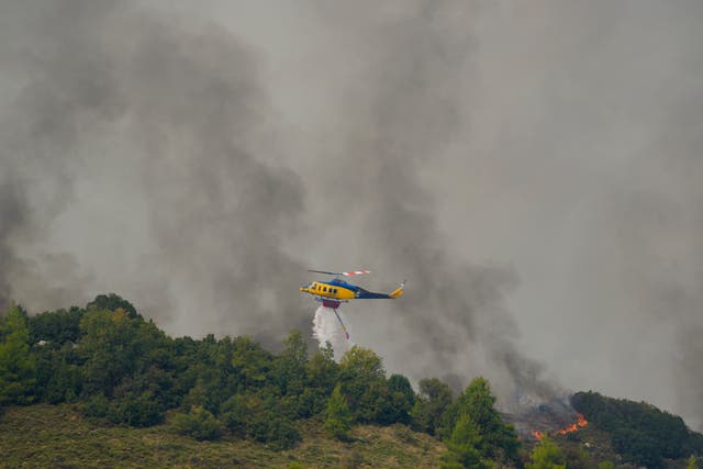 A helicopter drops water on flames in Sofiana village