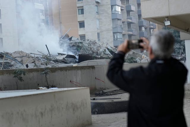 A man takes pictures of a residential complex hit by an Israeli airstrike in Dahieh, Beirut, Lebanon