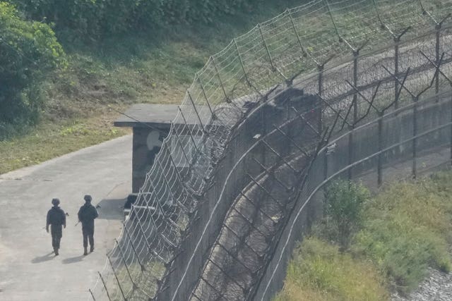 South Korean army soldiers patrol along a barbed-wire border fence