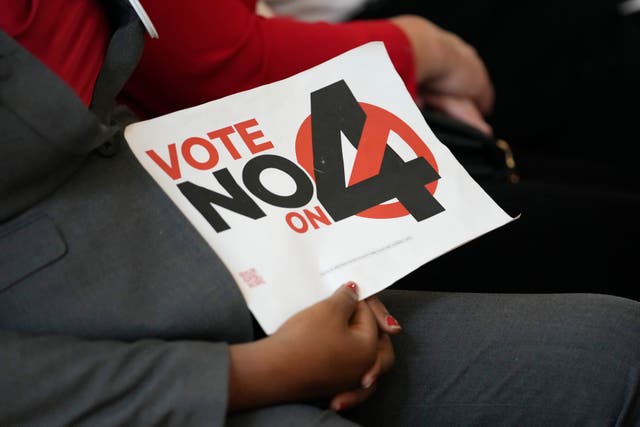 A person in the audience holds a sign against Amendment 4