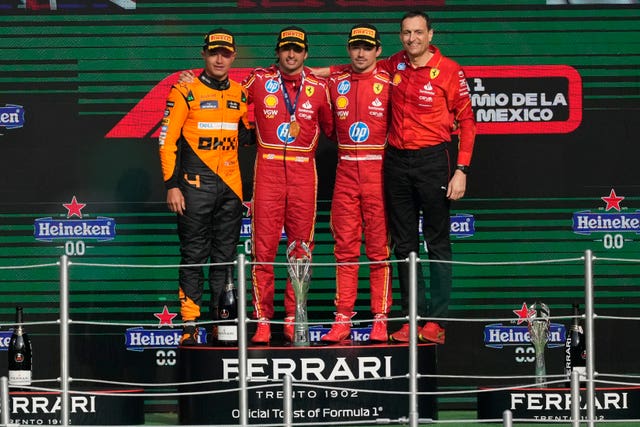 Lando Norris stands on the podium with the two Ferrari drivers and a Ferrari team member