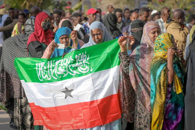 A woman displays the Somaliland flag as people queue to cast their votes during the presidential election
