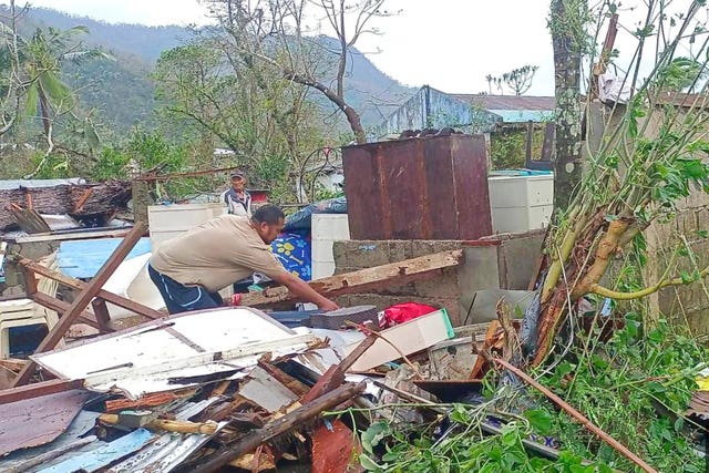A resident recovers belongings from their damaged home caused by Typhoon Man-yi