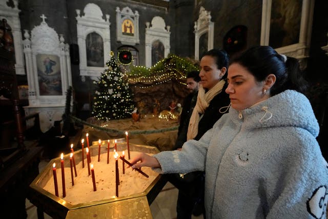 A woman lighting a candle in a church in Syria