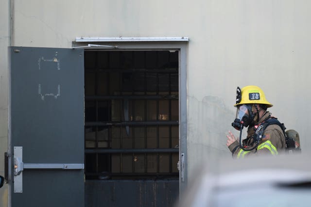 A firefighter enters a building where a plane crash occurred in Fullerton, Southern California