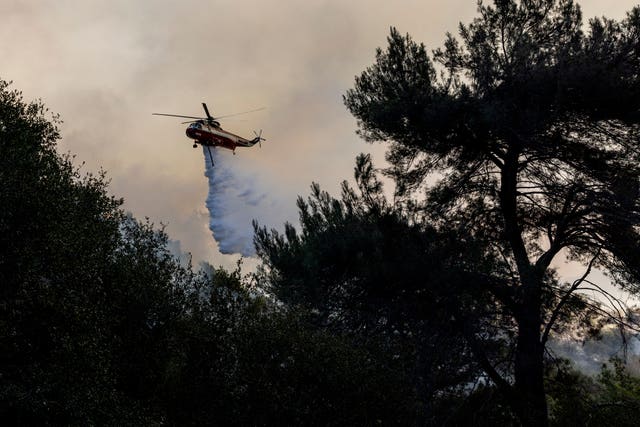 A firefighting helicopter releases water on a hot spot while battling the Palisades Fire in Topanga, California