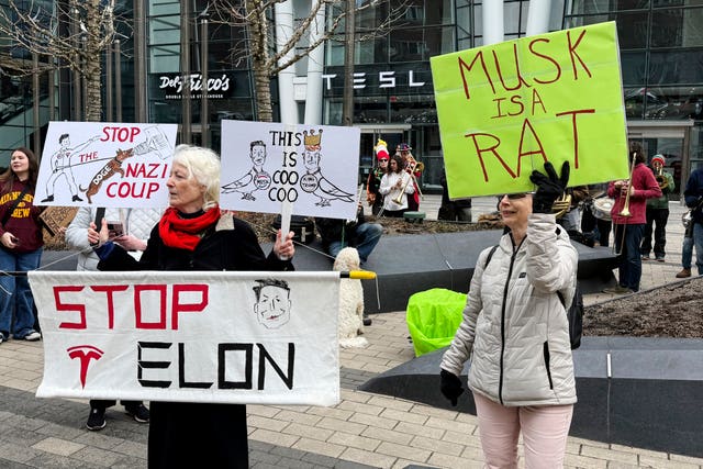 Protesters rally outside a Tesla store in Boston