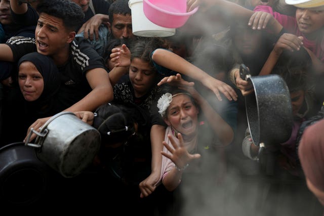 A Palestinian girl struggles as she and others try to get donated food