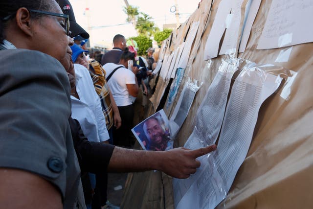 People searching for their missing relatives search a list of names outside the Jet Set nightclub