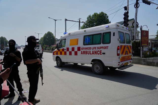 Ambulance driving past with soldiers standing on the roadside