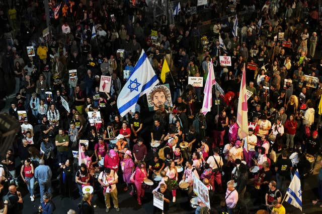 A large crowd people, some holding Israeli flags