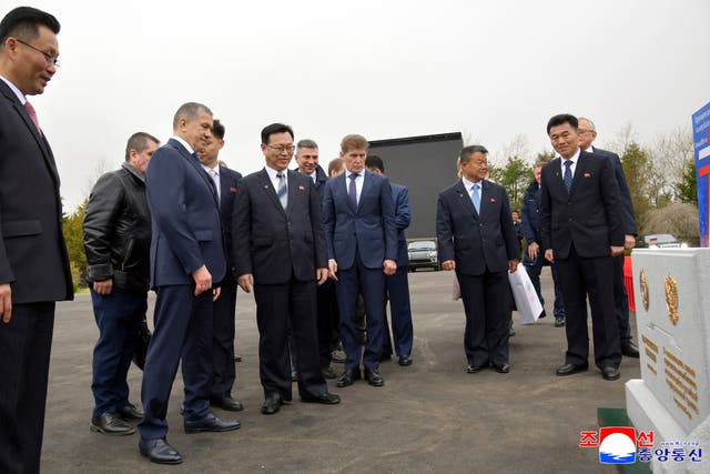 Officials from North Korea and Russia stand in front of a monument to mark a ground-breaking ceremony for the construction of a bridge between the two countries, in Rason Municipality, North Korea