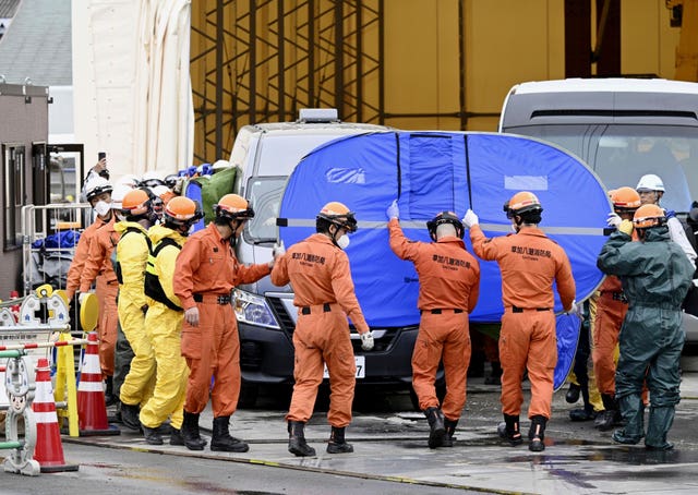 Rescuers with the recovered truck, covered in tarpaulin