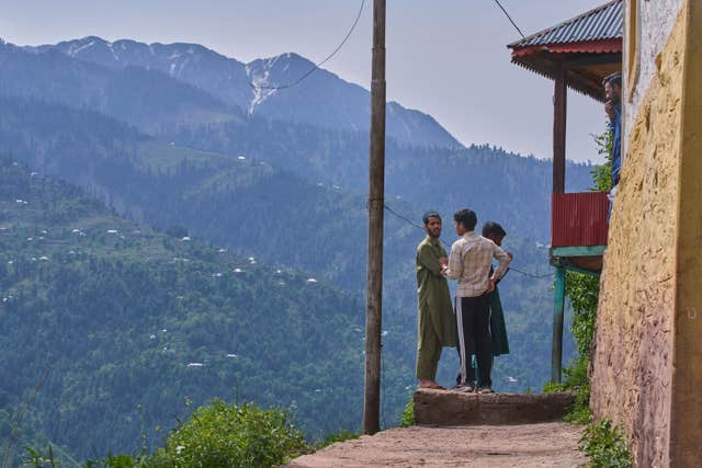 Kashmiri villagers stand outside their home