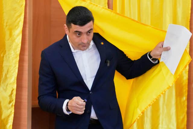 Presidential candidate George Simion exits a voting booth