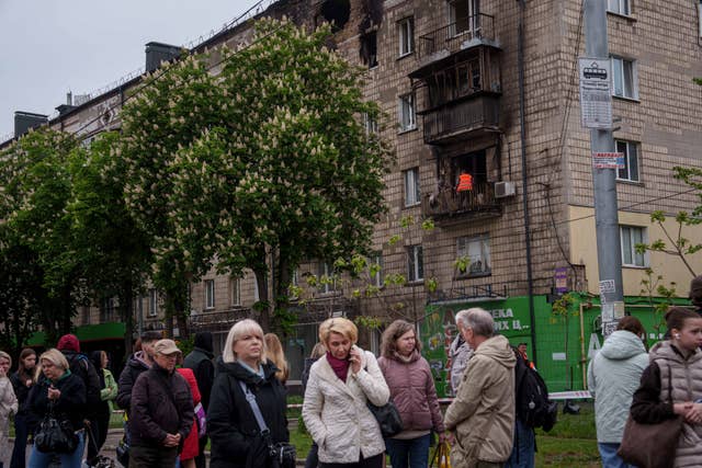 A municipal worker clears rubble from a balcony after a Russian strike in Kyiv