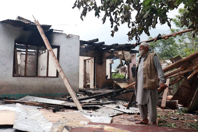 A resident stands next to a house damaged by Pakistani artillery shelling in Indian-controlled Kashmir